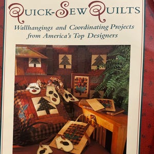 Peut inclure: Couverture de livre avec le titre "QUICK-SEW QUILTS" et le texte "Wallhangings and Coordinating Projects from America's Top Designers." L'image montre une courtepointe avec un motif d'arbre, un sac fourre-tout et d'autres articles matelassés.