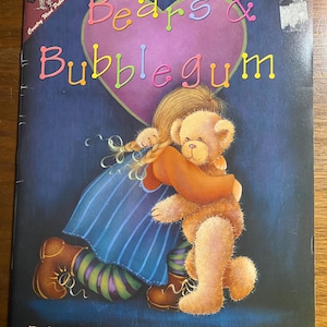 Op de afbeelding: Kinderboekcover getiteld "Bears & Bubblegum" met een meisje dat een teddybeer omhelst. De titel staat in kleurrijke bubbelletters boven een roze hart. Het meisje draagt een blauwe jurk en bruine laarzen. Het boek is van Linda Lock CDA.
