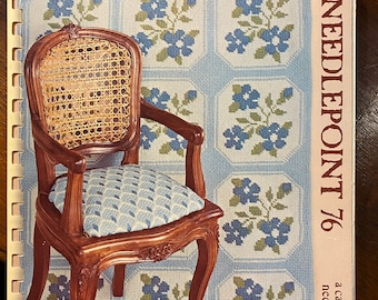 May include: A vintage "Needlepoint '76" calendar featuring a detailed illustration of a wooden chair with a woven back and patterned cushion. The background showcases a repeating floral design in blue and green.