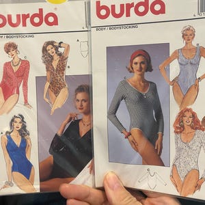 Puede incluir: Dos paquetes de patrones de costura Burda para bodies. Uno de los paquetes está etiquetado 4271, el otro 4270. Los paquetes presentan ilustraciones de los bodies en varios estilos, incluyendo encaje rojo, estampado de leopardo, encaje negro, azul y un patrón de cuadros blanco y negro.