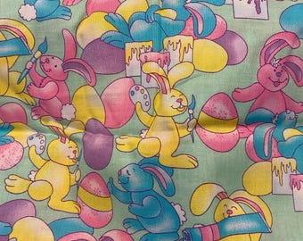 Pode incluir: Um tecido em tons pastel com um padrão repetido de coelhinhos da Páscoa a pintar ovos. Os coelhinhos são em tons de rosa, amarelo e azul, com ovos roxos e tubos de tinta. O fundo é verde claro.