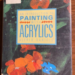 May include: Book cover featuring a painting of orange and blue flowers against a dark green background. The title reads "An Introduction to Painting with Acrylics" by Alfred Daniels.