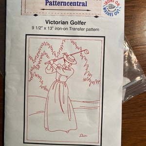 May include: A red line drawing of a Victorian woman playing golf. The image is a 9 1/2 inch by 13 inch iron-on transfer pattern. The text "IRONS ON WASHES OUT" is in a circle on the top right corner of the image.