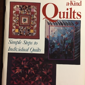 May include: Book cover with the title "One-of-a-Kind Quilts: Simple Steps to Individual Quilts" by Judy Hopkins. The cover features three quilt designs: a red and white quilt with a geometric pattern, a blue and white quilt with a floral pattern, and a dark red and black quilt with a leaf pattern.