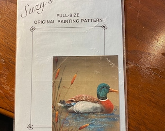Puede incluir: Un patrón de pintura original de tamaño completo que presenta un pato silvestre nadando en un estanque con espadañas. El patrón está impreso en una tarjeta blanca con texto azul que dice "Suzy's Full-Size Original Painting Pattern".