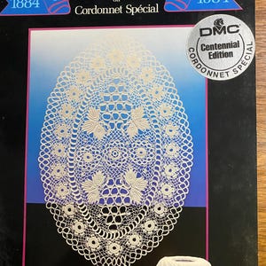 May include: A DMC Centennial Edition product featuring a detailed white lace doily design. The image includes text that reads "Centenaire du Cordonnet Spécial 1884-1984" and a ball of white thread. The DMC logo is visible.