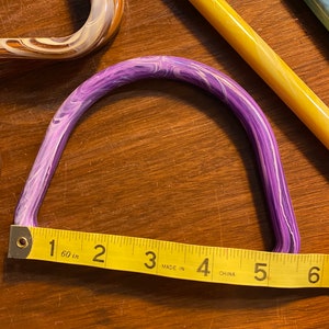 May include: A purple and white marbled plastic handle with a yellow measuring tape reading "1 60 in 2 3 MADE IN 4 CHINA 5 6".