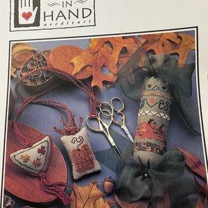 May include: A set of three fall-themed needlepoint fob patterns. The patterns feature a pumpkin, a cornucopia, and a trio of autumn leaves. The patterns are from Heart in Hand needle art.