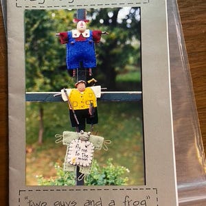 May include: A craft pattern booklet titled rag bag creations #71 featuring two guys and a frog. The cover displays three small fabric figures: a top figure in blue overalls, a middle figure in a yellow vest holding a fishing rod, and a bottom frog.