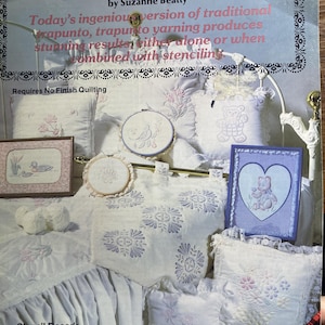 May include: A craft instruction book titled Trapunto Yarning by Suzanne Beatty, featuring a cover image of white fabric items decorated with trapunto and stenciled designs, including pillows, framed art, and embroidery hoops on a bed.