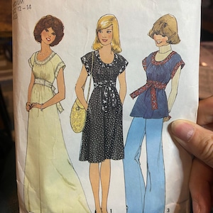 May include: A vintage sewing pattern for three different dresses. The pattern is for sizes 12-14 and is from Simplicity pattern number 7341. The dresses are all in different styles, one is a long flowing dress, one is a shorter dress with a polka dot pattern, and the third is a dress with a blue and white pattern and a matching pair of wide-legged pants.