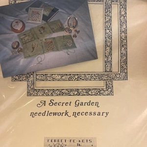 May include: A Secret Garden needlework kit. The kit includes a blue fabric with small embroidered designs, a booklet, and decorative frames. The text "A Secret Garden needlework necessary" is printed on the packaging.