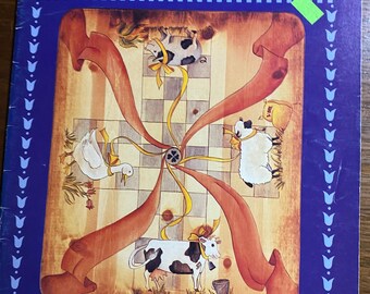 Puede incluir: Portada de libro titulada "I Like Country" con un diseño rústico. Incluye ilustraciones de animales de granja, como vacas y ovejas, con un borde azul y el texto "Over Twenty-five Country Designs to Delight the Decorative Painter."