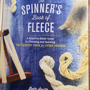 May include: A book titled "The Spinner's Book of Fleece" with a blue and white textured background. The book cover features text, yarn samples, and a spinning wheel. The book is a guide to choosing and spinning fleece.
