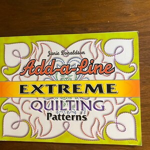May include: A yellow book with the title "Add-a-Line EXTREME QUILTING Patterns" by Janie Donaldson. The cover features a decorative design with a purple, red, and blue stitching pattern.