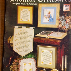 May include: A book cover with the title "Biblical Treasures" and a design by Soo-Z Alexander. The cover features several cross-stitch patterns with biblical verses and images of Jesus.