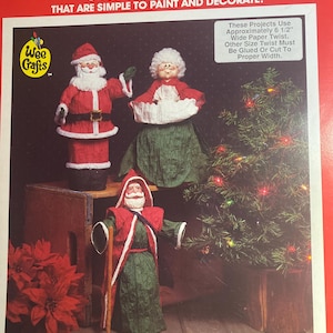 May include: A craft kit box titled "Decorate-A-Head" featuring gypsum Christmas heads. The box includes images of Santa Claus and Mrs. Claus figures, along with a Christmas tree. The text on the box says "That are simple to paint and decorate!"