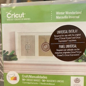May include: A Cricut Winter Wonderland image set cartridge box featuring a green and white design. The box displays text including Universal Overlay, 50+ unique images, and Anna Griffin branding. It shows two framed ornament illustrations.