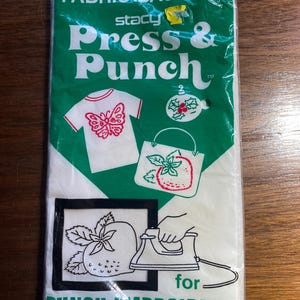 May include: A pack of Stacy Press & Punch Easy Iron-On Fabric Backing for punch embroidery. The pack is green and white with images of a butterfly, a holly ornament, and a strawberry. The text "for PUNCH EMBROIDERY" is printed on the pack. Makes punch embroidery stitching better than ever - even on knits.