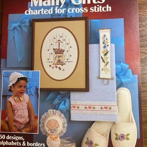 May include: A vintage craft leaflet titled "Many Gifts" for cross stitch, featuring a framed cross-stitch design, a small girl in a pink outfit, and other cross-stitch projects. The leaflet is designed by Anne Van Wagner Young.