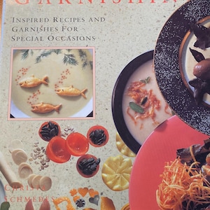 Puede incluir: El libro de la guarnición: Recetas inspiradas y guarniciones para ocasiones especiales, un libro de cocina con una portada colorida que presenta imágenes de guarniciones de comida, incluyendo pescado, tomates y fideos.