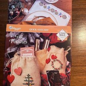 May include: Two cross stitch patterns for gift pouches. One pattern features a Christmas tree and the other a wreath. The patterns are from the Cross Stitch Collector's Series.