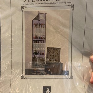 May include: A Cotton Case, a beaded sewing case for embroidery cotton. The case is lavender with a hanging design and multiple pockets. The image also shows a small brown case and a brown box. The text on the case reads "A Cotton Case".
