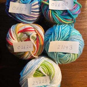 May include: Five balls of yarn in different colors and patterns. The yarn is labeled with numbers: 02135, 02600, 02626, 21143, and 23223.