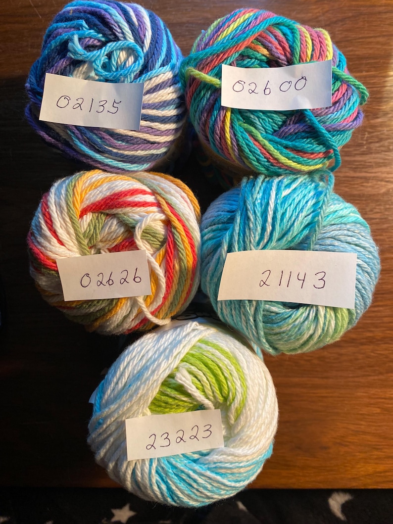 May include: Five balls of yarn in different colors and patterns. The yarn is labeled with numbers: 02135, 02600, 02626, 21143, and 23223.