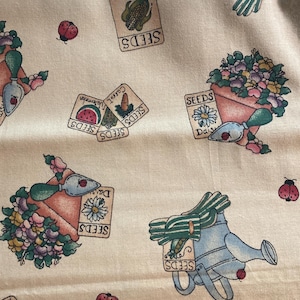 May include: A beige fabric featuring a repeating pattern of gardening items including light blue watering cans, terracotta pots filled with colourful flowers, small hand trowels, red ladybirds, and seed packets labelled with corn, carrot, and watermelon.