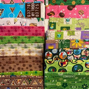 Puede incluir: Una colección de piezas de tela coloridas con varios patrones y texto. Los diseños incluyen galletas Girl Scout, triángulos, flores y texto como "Helpful" y "Courage". Las telas están apiladas, mostrando una variedad de colores y temas.