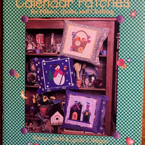 May include: A book titled "Calendar Patches for Pillows, Quilts, and Clothing" by Nancy J. Smith & Lynda S. Milligan. The cover features a green and white checkered background with a bookshelf displaying three pillows with different designs. The pillows are decorated with a basket of flowers, a snowman, and a birdhouse.