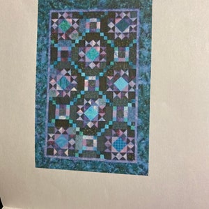 May include: A quilt with a blue, black, and purple patchwork design. The quilt is made up of squares and triangles, and it has a dark blue border.