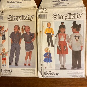 Könnte beinhalten: Zwei Simplicity-Schnittmuster mit Walt Disney-Charakteren. Das Muster auf der linken Seite ist für die Größen 4, 5 und 6 und zeigt ein Mickey Mouse-Design. Das Muster auf der rechten Seite ist für die Größen 4, 5 und 6 und zeigt ein Mickey Mouse-Design.