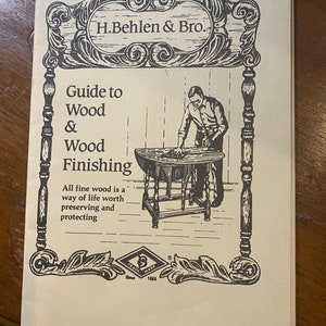 May include: A black and white illustration of a man working on a wooden table. The text reads "H.Behlen & Bro. Guide to Wood & Wood Finishing. All fine wood is a way of life worth preserving and protecting. Trade Mark Since 1883."