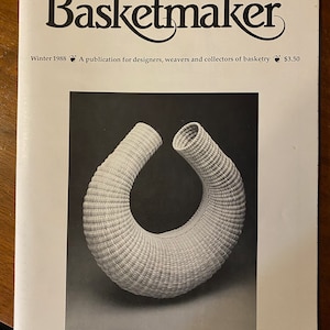 May include: A black and white photograph of a woven basket shaped like a circle. The basket is made from natural materials and has a smooth, even texture.