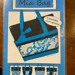 Może przedstawiać: Wzór szycia na niebieską i czarną torbę typu tote zwaną "The Mia Bag". Wzór zawiera pięć odwracalnych opcji pokrycia i ma wymiary 38 cm szerokości, 26,5 cm wysokości i 12,5 cm głębokości. Wzór pochodzi od Silk Road Creations.