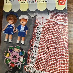 Puede incluir: Portada de un libro de patrones de ganchillo vintage titulado "Crochet Money-Makers FOR YOUR BAZAAR". La portada presenta dos muñecas con trajes de ganchillo, un artículo de ganchillo a cuadros rojos y blancos y un portahilos en forma de flor. El precio es de 10 céntimos.