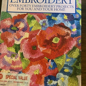 Könnte beinhalten: Ein Taschenbuch mit dem Titel EMBROIDERY OVER FORTY EMBROIDERY PROJECTS FOR YOU AND YOUR HOME von Una Stubbs. Das Cover zeigt ein lebendiges, detailliertes Blumenstickmuster in Rot-, Rosa-, Blau- und Grüntönen sowie einen Preisaufkleber.