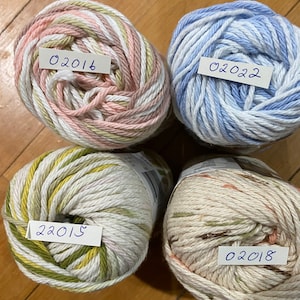 May include: Four balls of yarn in different color combinations. The yarn is white with stripes of pink, green, blue, and brown. Each ball has a handwritten label with a date: 02015, 02016, 02018, and 02022.