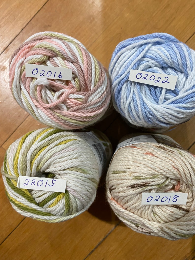 May include: Four balls of yarn in different color combinations. The yarn is white with stripes of pink, green, blue, and brown. Each ball has a handwritten label with a date: 02015, 02016, 02018, and 02022.