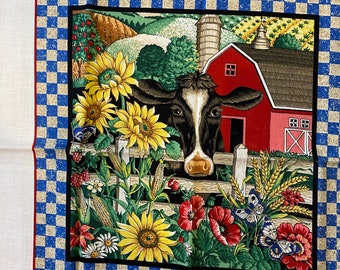 Könnte beinhalten: Ein Stoffpaneel mit einer zentralen Illustration einer schwarz-weißen Kuh hinter einem Holzzaun, umgeben von Sonnenblumen, Mohnblumen, Mais und Schmetterlingen, mit einer roten Scheune im Hintergrund, eingerahmt von einem blau-weißen Karomuster.