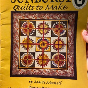 May include: A yellow book cover titled "SUNBURST Quilts to Make" features a quilt pattern with sunflower designs in red, yellow, and brown. The cover includes text by Marti Michell and mentions "Perfect Patchwork Templates."