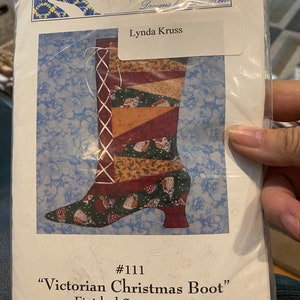 May include: A pattern for a Victorian Christmas boot quilt. The pattern is for a boot with a red, green, and brown patchwork design. The finished size is 8 inches by 18 inches.
