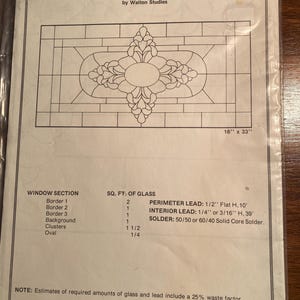 May include: A black and white line drawing of a stained glass window pattern. The pattern features a large oval in the center surrounded by clusters of leaves. The drawing includes the title "HIDDEN HOUSE WINDOW PATTERN W-18 by Walton Studios" and the dimensions "16" x 33". The drawing also includes a table listing the square footage of glass needed for each section of the window.