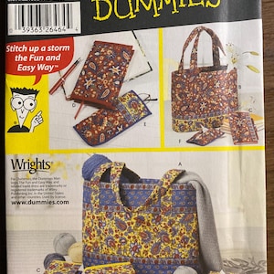 以下が含まれることがあります： Simplicity 5598のDummies向け裁縫型紙封筒。布製のバッグ、ケース、オーガナイザーの作り方が記載されています。表紙には、赤と黄色の配色で花柄のペイズリープリントが施された完成品のイラストが描かれています。