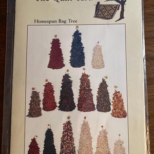 Könnte beinhalten: Ein Schnittmuster für Homespun Rag Trees. Das Cover zeigt verschiedene Rag Tree-Designs in verschiedenen Farben, jedes mit einem Stern. Der Text lautet "The Quilt Yard" und "Homespun Rag Tree".