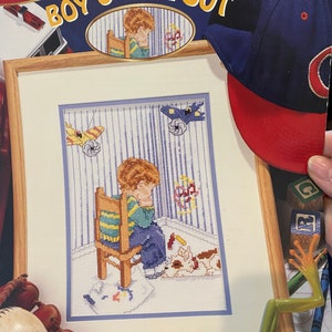 May include: Cross stitch pattern for a boy sitting in a chair with the words "Boy's Time Out" above the design. The frame size is 11 inches by 14 inches and the design size is 6.5 inches by 9.5 inches.