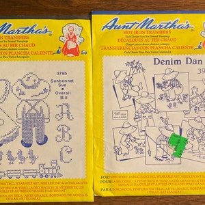 May include: Two yellow packages of iron-on transfer patterns for crafts. The left package features a design of a girl and boy in overalls with a train and birds. The right package features a design of a boy in overalls with a fishing pole and a bird. The text on the packages reads "Hot Iron Transfers" and "Each Design Good for Several Stampings".