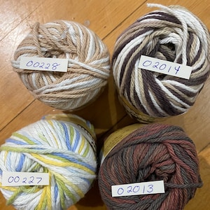 May include: Four balls of yarn in different color combinations. The yarn is striped with white, brown, blue, yellow, and red. The yarn balls are labeled with numbers: 00228, 02014, 00227, and 02013.